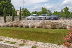 Casa vacanze alle Mura في تشفيدالي ديل فريولي: ثلاث سيارات متوقفة خلف جدار حجري