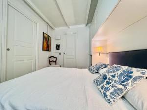 Un dormitorio con una cama blanca con almohadas azules y blancas en ComeCasa Entire House Port View - Two Bedrooms, en Saint-Tropez