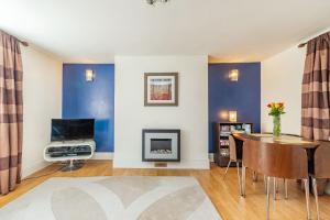 d'un salon avec des murs bleus, une table et une télévision. dans l'établissement 8A Wellington Terrace, à Whitby