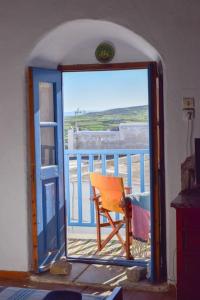 an open door with a chair on a balcony at Το πάνω σπίτι της Μαριάνθης in Márpissa