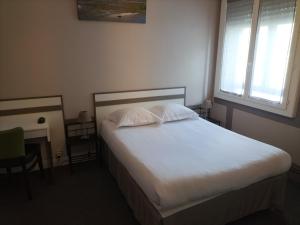Schlafzimmer mit einem Bett mit weißer Bettwäsche und einem Fenster in der Unterkunft Hôtel de France La Teste Arcachon in La Teste-de-Buch