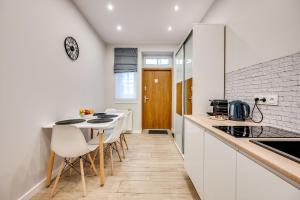 a kitchen with white cabinets and a table and chairs at Central Platinum Apartments 26 in Rybnik