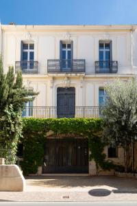 Uma casa branca com hera na frente. em Casa-Belle Chambres d hotes em Sérignan