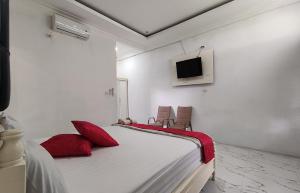 New The Heritage Resort & Restaurant Bukit Lawang في Bandartelu: غرفة نوم بسرير ومخدات حمراء وتلفزيون