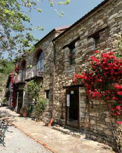 an old stone building with red flowers on it at Cascina Bertolotto Wine Resort in Spigno Monferrato