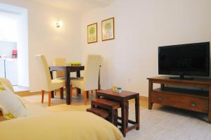 a living room with a television and a table with chairs at Guesthouse Adriana Cottages in Labin +9 photos
