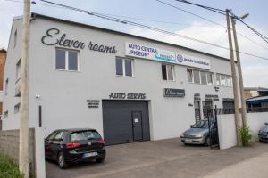 ein weißes Gebäude mit zwei Autos auf einem Parkplatz in der Unterkunft ELEVENROOMS in Belgrad