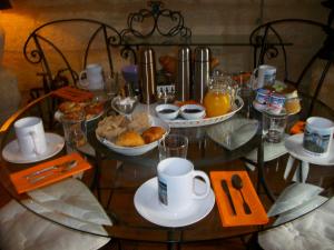 a glass table with breakfast foods and cups on it at Domaine de Monein in Saint-André-de-Cubzac
