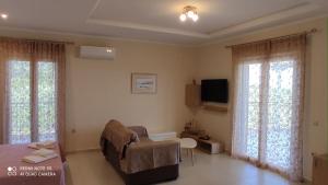 a living room with a couch and a tv and windows at Kalliope Apartments in Tsoukalades