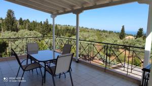 a house with a balcony with a table and chairs at Kalliope Apartments in Tsoukalades