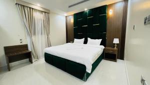 - une chambre avec un grand lit et une tête de lit verte dans l'établissement فندق فخر ينبع 5, à Yanbu