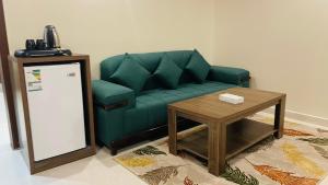 فندق فخر ينبع 5 في ينبع: غرفة معيشة مع أريكة خضراء وطاولة