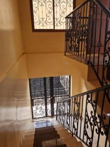 un escalier avec des balustrades noires et une fenêtre dans l'établissement KARIBU G&H Location Meublée Furnished Rental, à Yaoundé