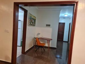 Cette chambre comprend une table, une chaise et un miroir. dans l'établissement KARIBU G&H Location Meublée Furnished Rental, à Yaoundé