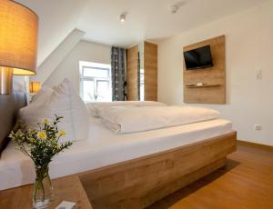 Hotelgasthof Bayerischer Hof في زولتسباخ-روزنبرغ: غرفة نوم مع سرير كبير وتلفزيون على الحائط