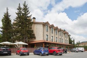 un gran edificio con coches estacionados en un estacionamiento en Hotel Iriguibel Huarte Pamplona, en Huarte