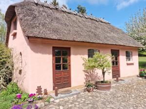 a small pink house with a thatched roof at Liebhaveri i særklasse in Årup