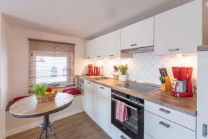 uma cozinha com armários brancos e uma pequena mesa em SEASIDE APARTMENTS - TOWNHOUSE em Eckernförde