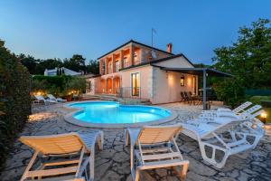 a backyard with a pool and chairs and a house at Villa Imagine in Višnjan