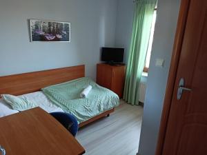a small bedroom with a small bed and a table at Zajazd Stary Młyn in Świdwin +1 photo