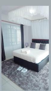 Schlafzimmer mit einem Bett und einem Paar Hausschuhen in der Unterkunft Sofitel 4 bedrooms maisonette Milimani in Kisumu