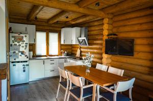 a kitchen with a table and chairs and a refrigerator at Osada Dzika - domy z bali in Uherce Mineralne (7)