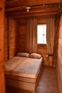uma cama num quarto de madeira com uma janela em Hospedagem Mística em São Tomé das Letras