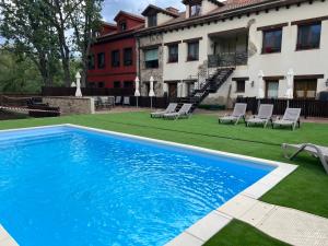 una piscina en un patio con sillas y un edificio en Casa de Navalhorno Valsain, en La Pradera de Navalhorno