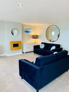 a living room with a blue couch and a mirror at The Beachfront Lookout a Stunning Apartment with Perfect Sea View in Worthing