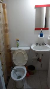 La salle de bains est pourvue de toilettes blanches et d'un lavabo. dans l'établissement TRINIDAD, à San Juan