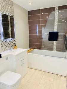 a bathroom with a toilet and a tub and a sink at The Beachfront Lookout a Stunning Apartment with Perfect Sea View in Worthing +14 photos