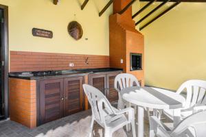 a kitchen with a white table and white chairs at Casa Guaratuba-Barra do Saí - "Recanto de Milady" - 80 m da Praia in Guaratuba