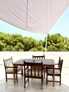 a wooden table and chairs under a white umbrella at Dimora delle Tonnare in Favignana