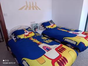 2 Betten in einem Schlafzimmer mit einer Superheldenbettdecke in der Unterkunft CASA BEATLES DEL VALLE in Pinos del Valle