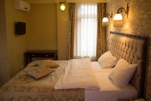 um quarto com uma cama com lençóis brancos e almofadas em Cheers Hostel em Istambul