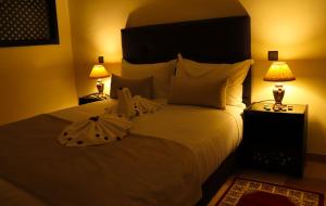 a bedroom with a large white bed with two lamps at Hôtel Riad Salam Agadir in Agadir