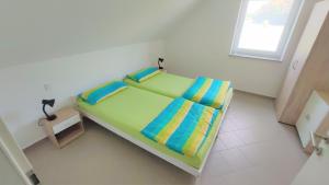 - un lit vert dans une chambre blanche dotée d'une fenêtre dans l'établissement Ferienwohnung Karola beim Legoland, à Ichenhausen