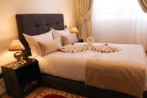 a bedroom with a large white bed with two pillows at Hôtel Riad Salam Agadir in Agadir