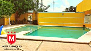 a swimming pool in front of a yellow building at Hotel El Marques in Mérida