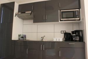 a kitchen with black cabinets and a microwave at Pension Hänse in Weimar