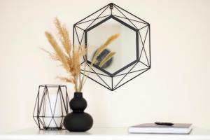 a black geometric mirror with a vase and a book at TREND BA HOME Apartman in Balatonalmádi