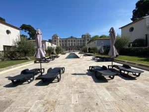 a courtyard with benches and umbrellas and a pool at **LOVELY APARTMENT IN THE CASTLE OF LA REDORTE** in Laredorte