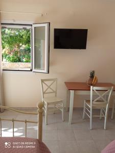 a dining room with a table and a tv on the wall at Studios Dimitra in Spartià