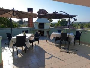 two tables and chairs with umbrellas on a patio at Apartments Villa Elda in Peroj