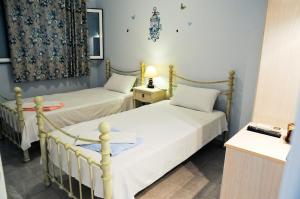 two twin beds in a room with two lamps at Studios Dimitra in Spartià