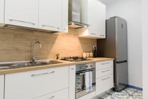 una cucina con armadi bianchi e frigorifero in acciaio inossidabile di SYMPHONY HOUSE a Sorrento
