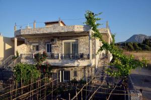 une vieille maison en pierre avec un balcon dans une rue dans l'établissement Stone Villa, à Corinthe