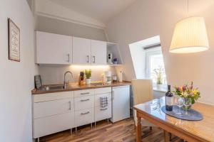 a kitchen with white cabinets and a wooden table at Captains Haven in Eckernförde