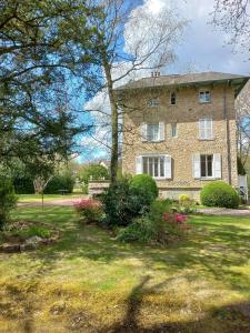 ein großes Backsteinhaus mit einem Rasenhof in der Unterkunft Villa Matignon in Bagnoles de l'Orne