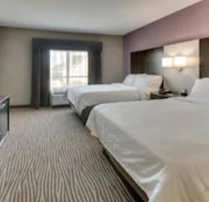 um quarto de hotel com três camas e uma janela em Holiday Inn Express & Suites Cheektowaga North East, an IHG Hotel em Cheektowaga